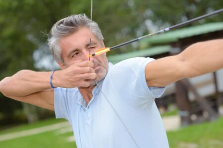 senior man aiming a bow and arrow